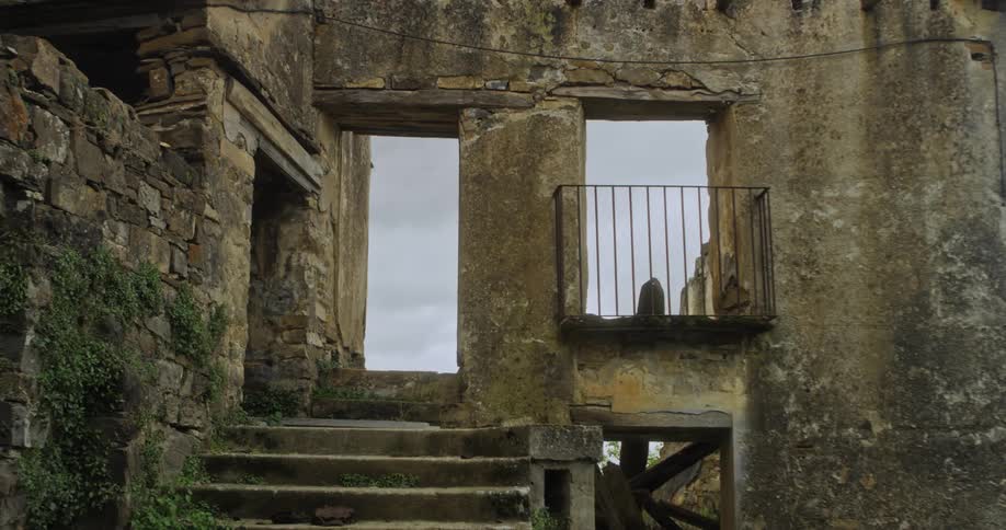 Stairs lead to the entrance of an abandoned and dilapidated building