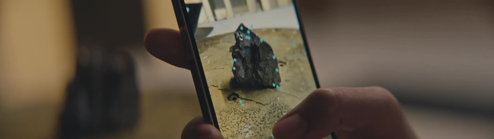 A hand holds a phone filming a mineral and applying marker dots