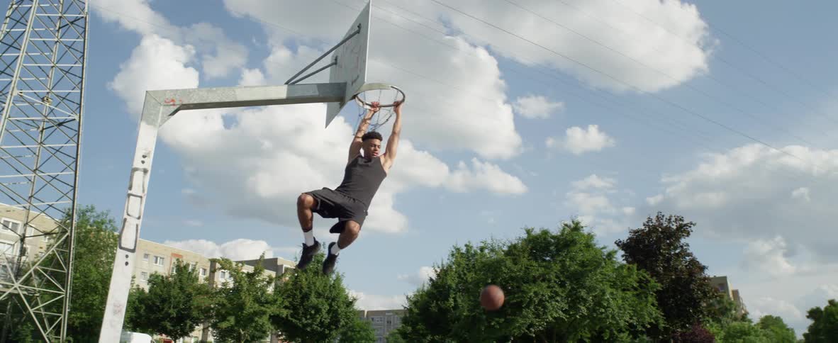 A man dribbles a basketball and dunks it