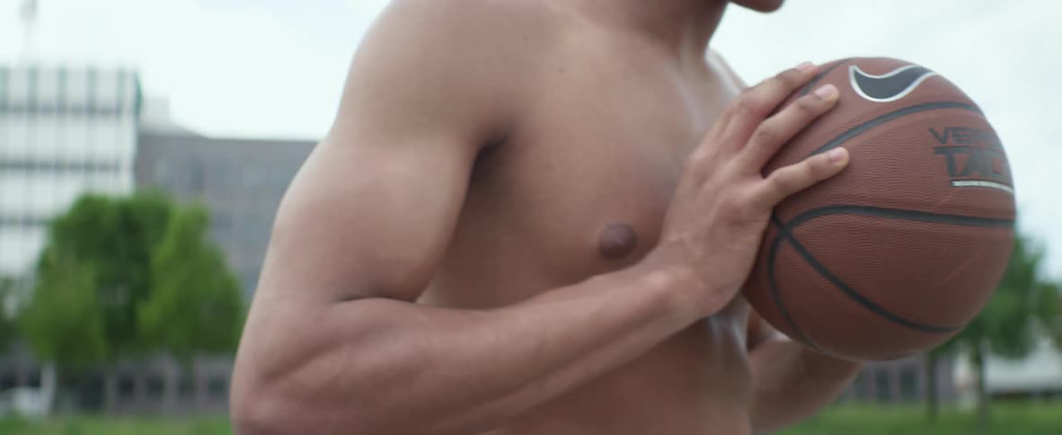 Shirtless black young man holding a basketball and looking uneasy