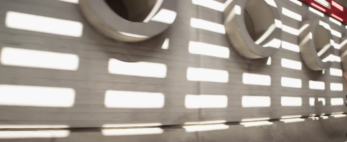 A man sprints through a concrete tunnel with wall cutouts