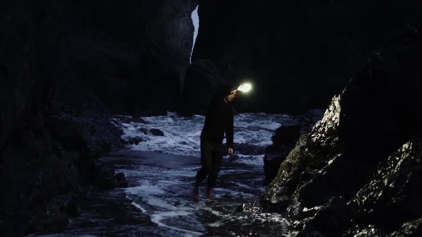 A person in a cave next to the sea