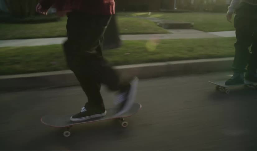 Three teens ride skateboards down a neighborhood street