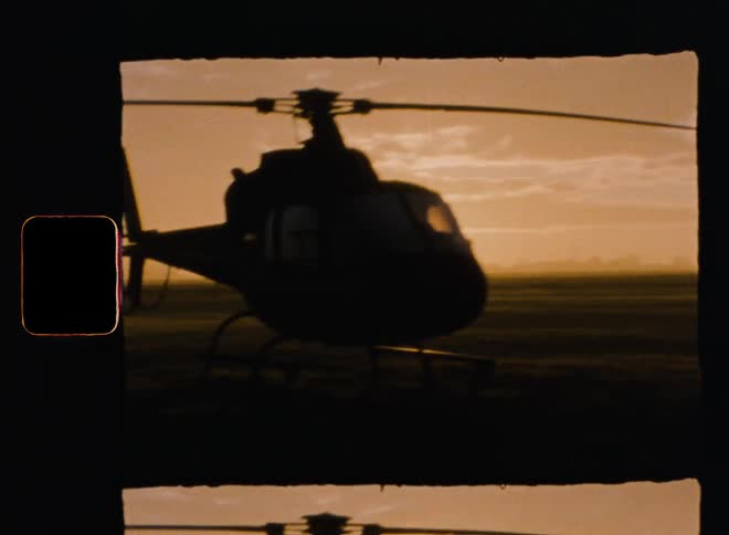Helicopters sit on grassy field under a cloudy sky
