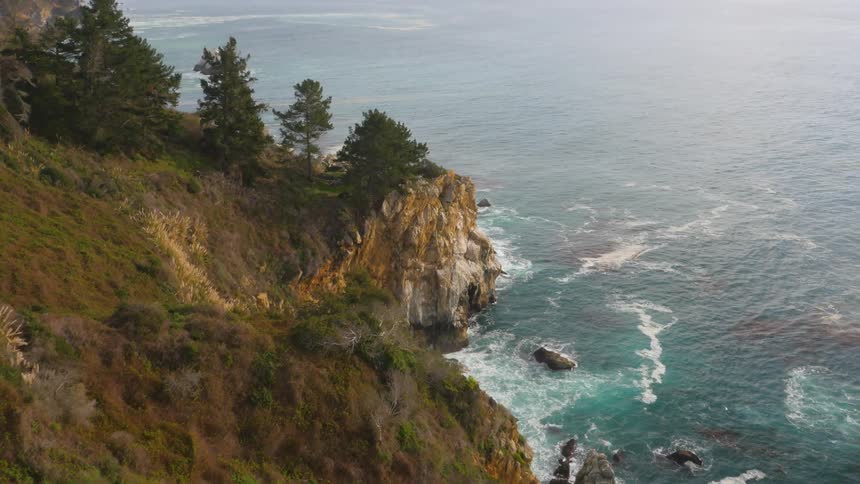 Ocean waves break against the cliff side