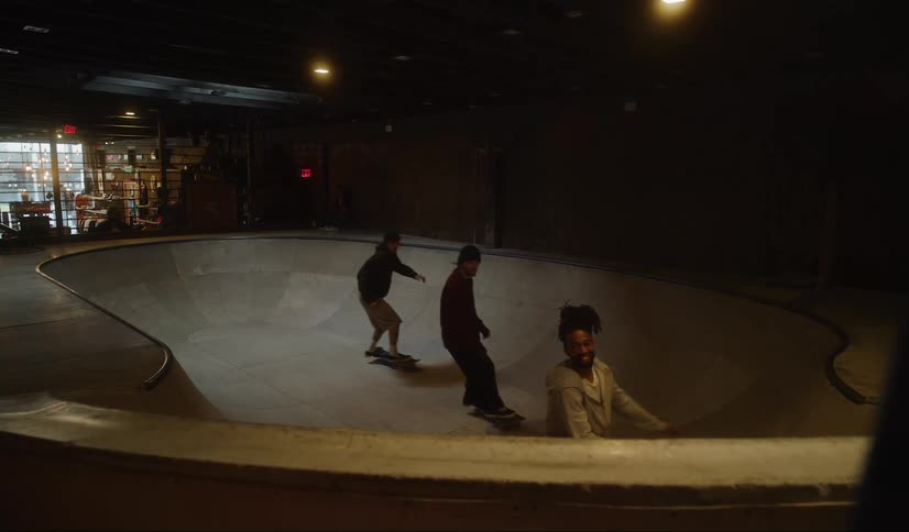 Three men ride their skateboards in an indoor skate park
