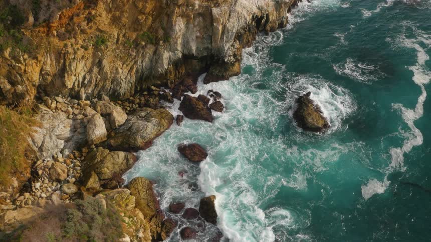 Aerial view of the coastline as waves splash against the rocks