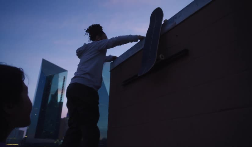 A woman climbs up on the roof of the tall building