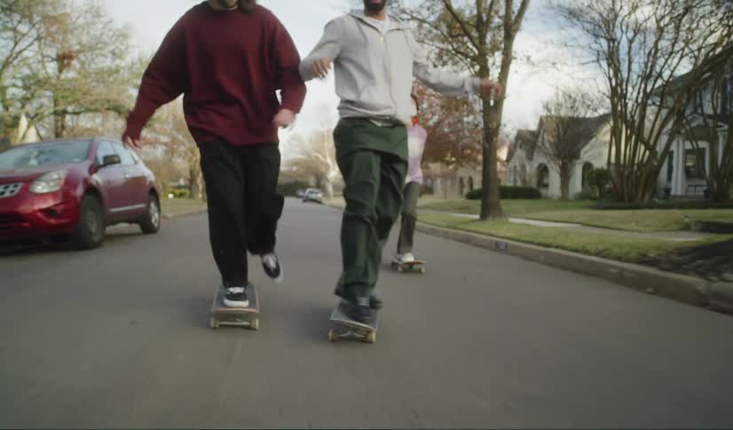 A group of men skateboard together in a quiet neighborhood
