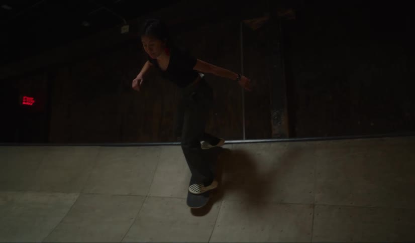 A teenage girl skateboard down a ramp and back up and jumps off as a boy watches her