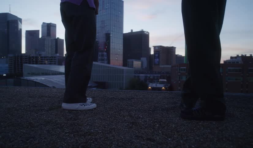 Two people stand on a plot of gravel downtown