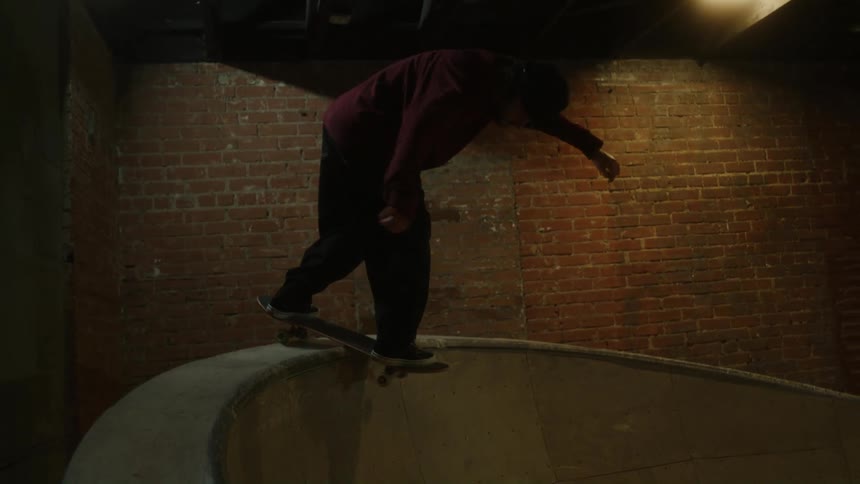 Man skateboards up the sides and across the center of skatepark bowl