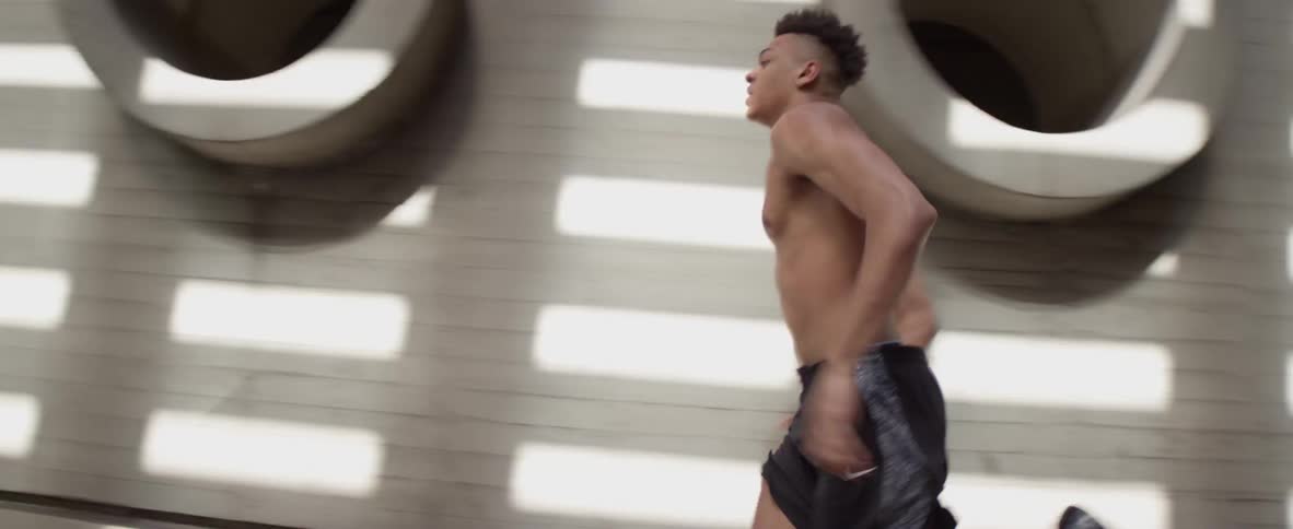 A man runs next to a wall in what seems to be a like gym