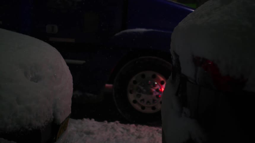 A truck drives on a snowy road during night