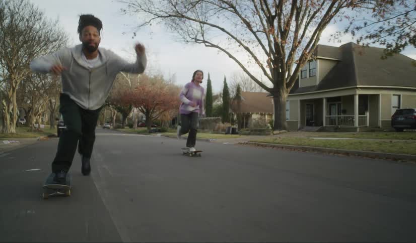 A group of three friends skateboard on a neighborhood street