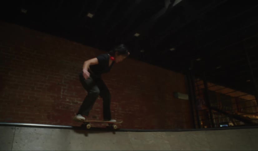 Asian woman and black man skating and doing stunts at an indoors skate park