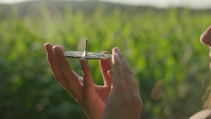 A teenage girl is standing outside holding a sundial in her hand