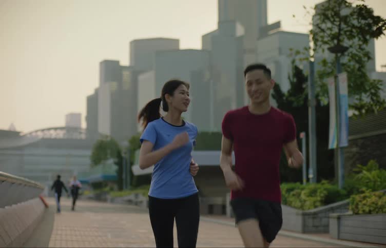 Asian man and woman wearing fitness clothing jogging and talking together at a public park