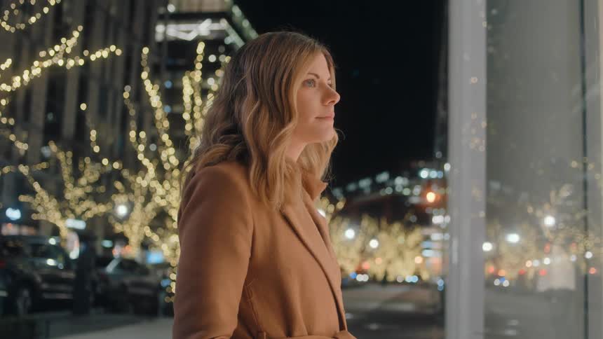 A woman walking down the sidewalk stops to window shop