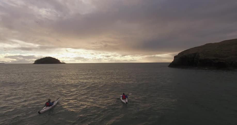 Kayakers paddle on the ocean on a cloudy day