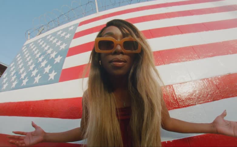 A woman leans forward by the painting of an american flag