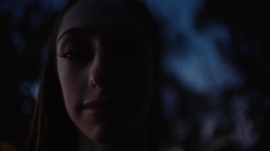 Woman with straight hair looking at camera outdoors at dusk