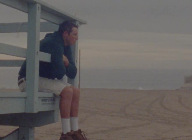 A man sits on the lifeguard stand on the beach