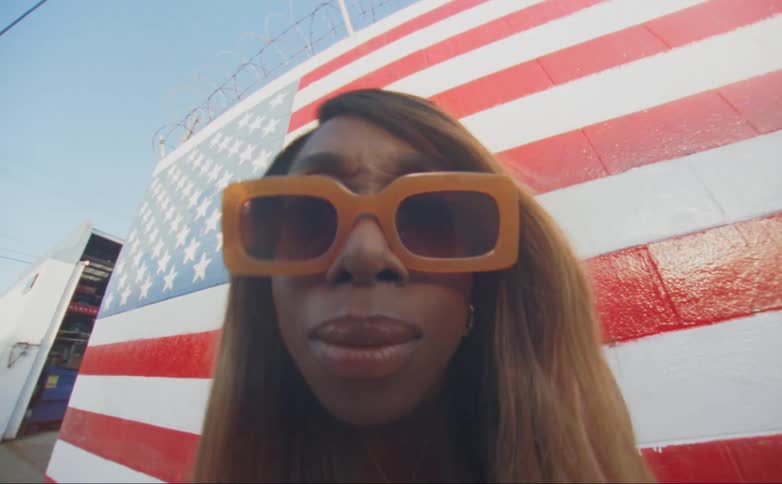 A woman stands by a wall painted with the american falg