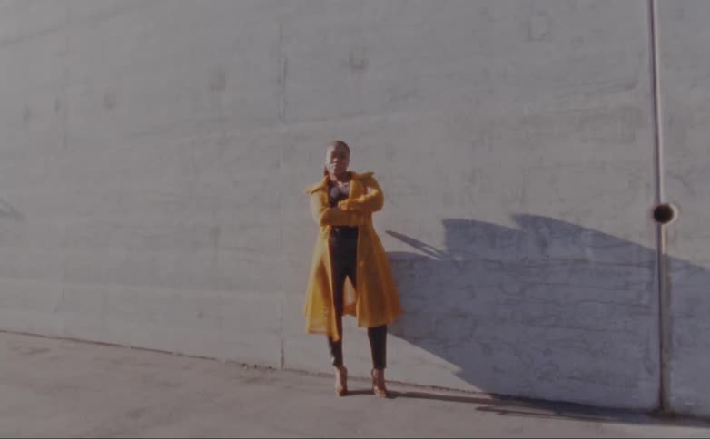 A woman stands with her arms crossed in front of a wall