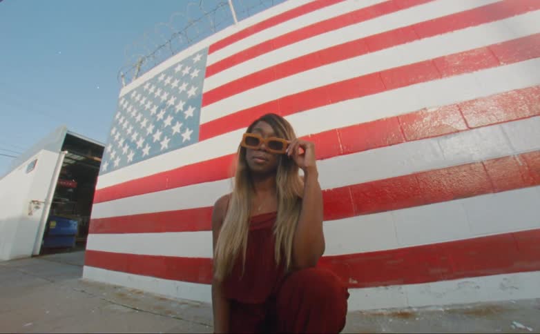 Woman half kneels on sidewalk near wall painted with american flag