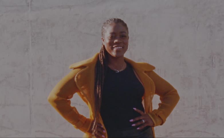 Woman with dreadlocks yellow jacket and black shirt poses for the camera