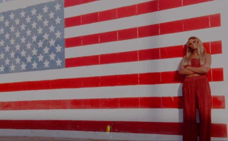 A woman poses by the wall with an american flag painted on it