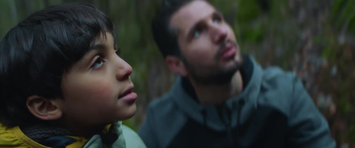 A man and child look at something and smile