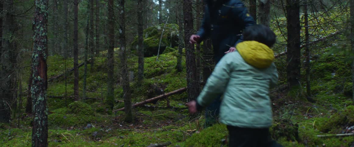 Father and son wearing coats running around on the forest playing tag
