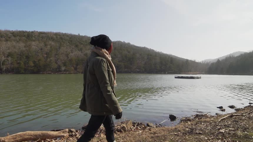 A girl walks along a river bank