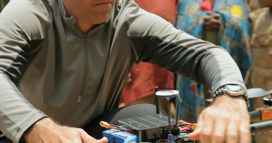 A man fixes a machine in front of a group of children