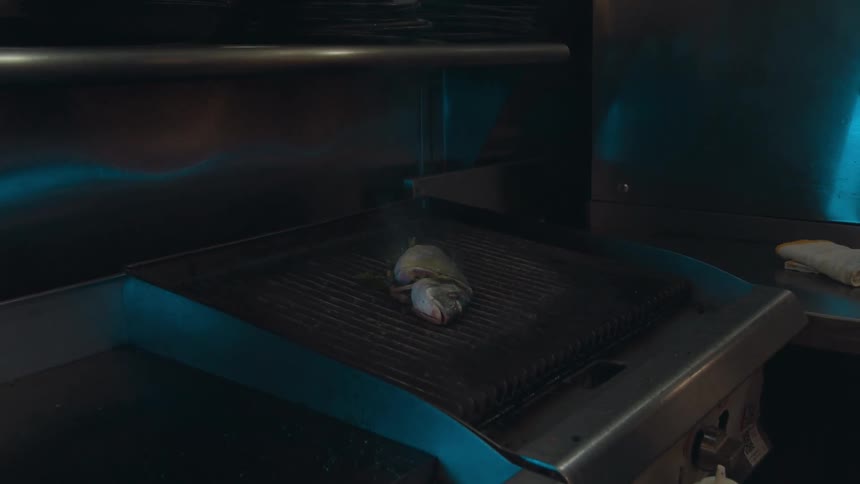 A man places seafood on a restaurant grill