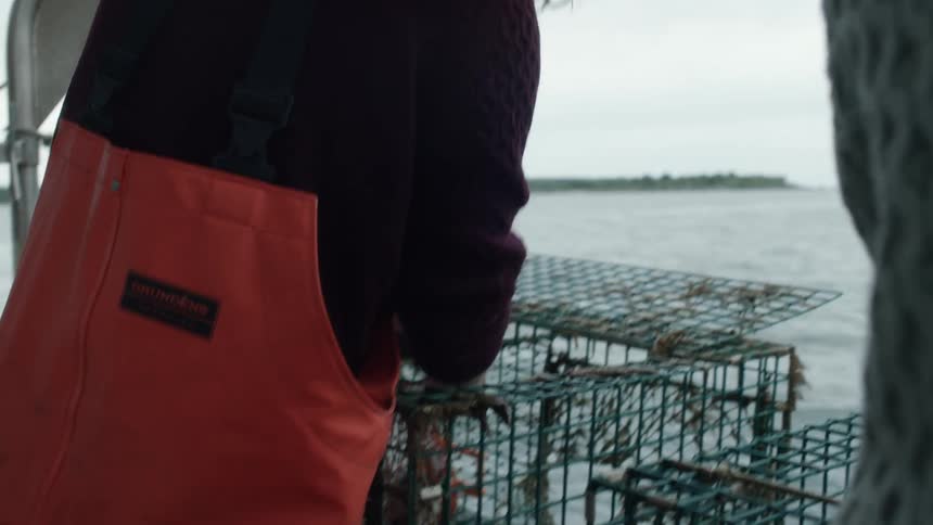Two fisherman chat while cleaning cages on a boat