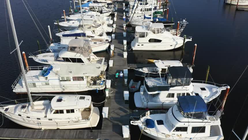 Aerial view of boats in a marina and two people are walking on the dock