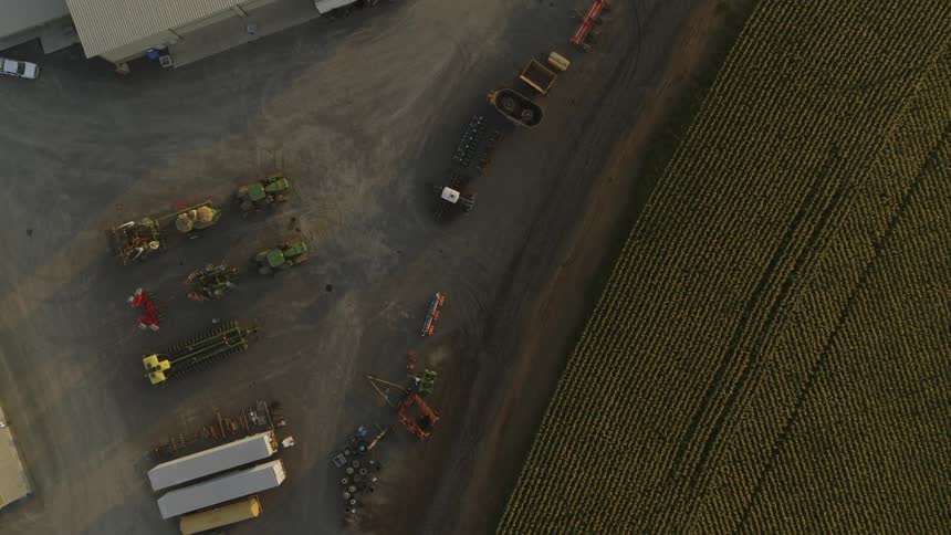 Top down view of farm equipment parked next to rows of crops