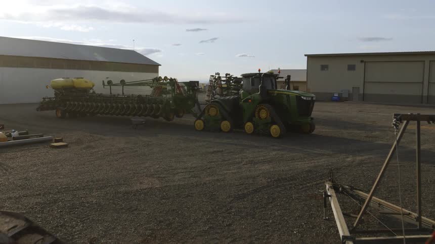 Slow push through various farm equipment towards a large and modern planting tractor equipped with tracks