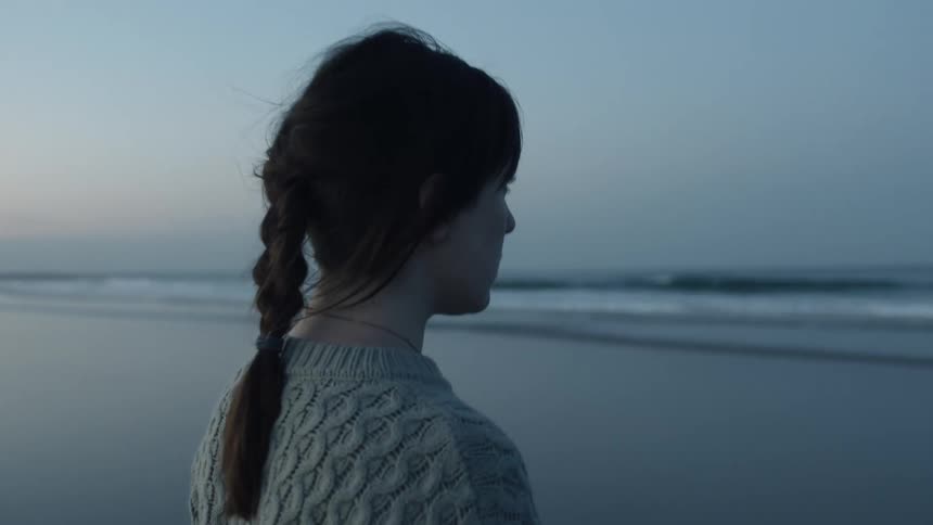 A woman walks up to another on the beach
