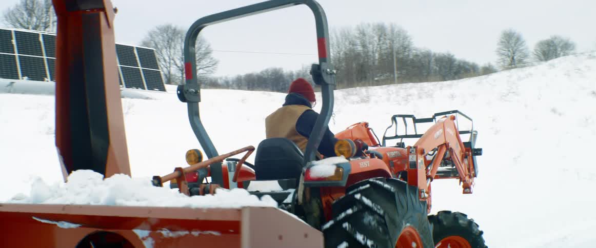 A man drives a snowplow in a rural area