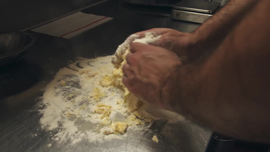 A restaurant chef kneads dough to make pasta