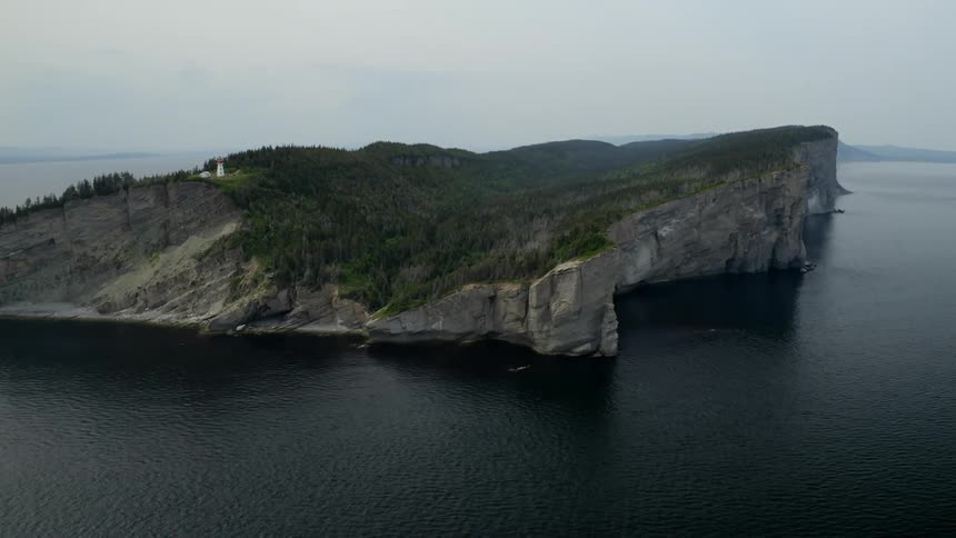 A lighthouse sits atop a small island in the ocean