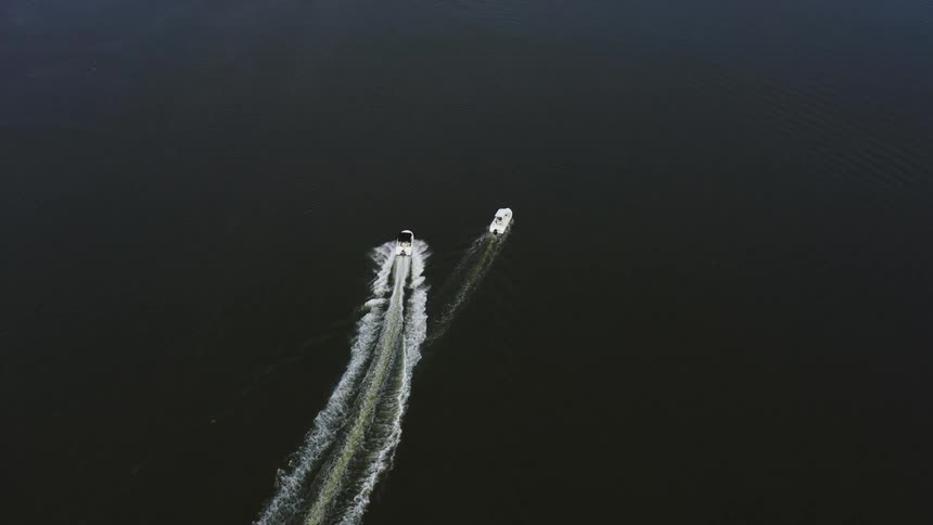 Aerial view of a boat speeding and passing another boat at the lake