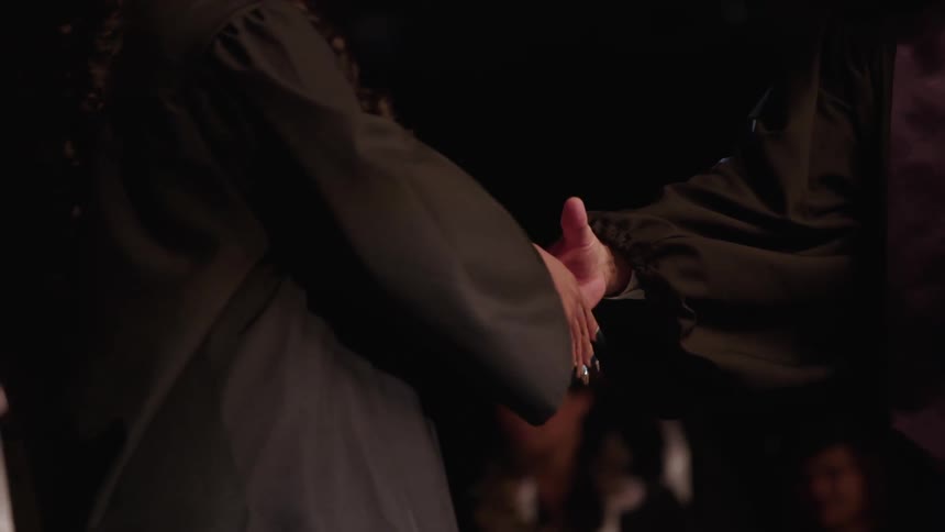 Closeup of college graduate shaking hands with college president