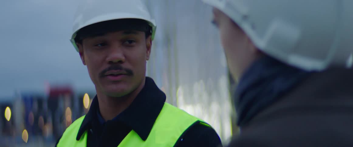 A construction worker talks with a woman outside