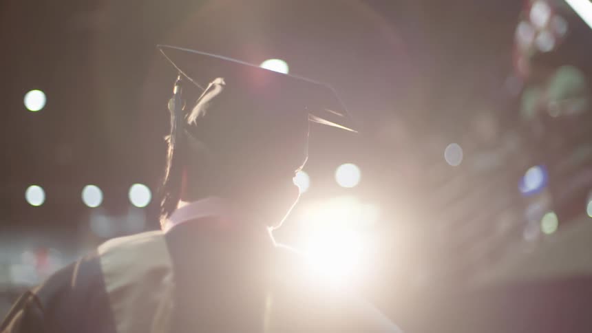 Man in a graduation outfit walks out in front of the audience at a graduation ceremony