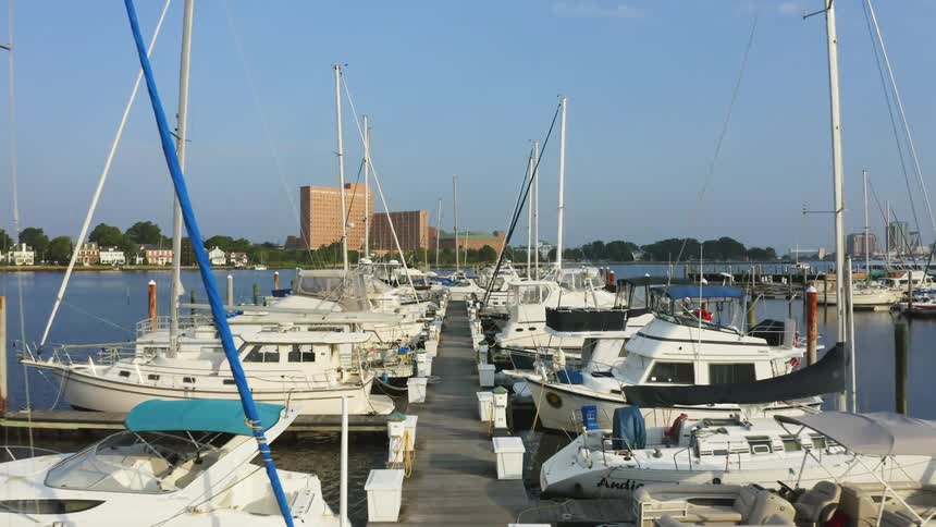 Drone view of sailboats docked on marina with skyline in the distance